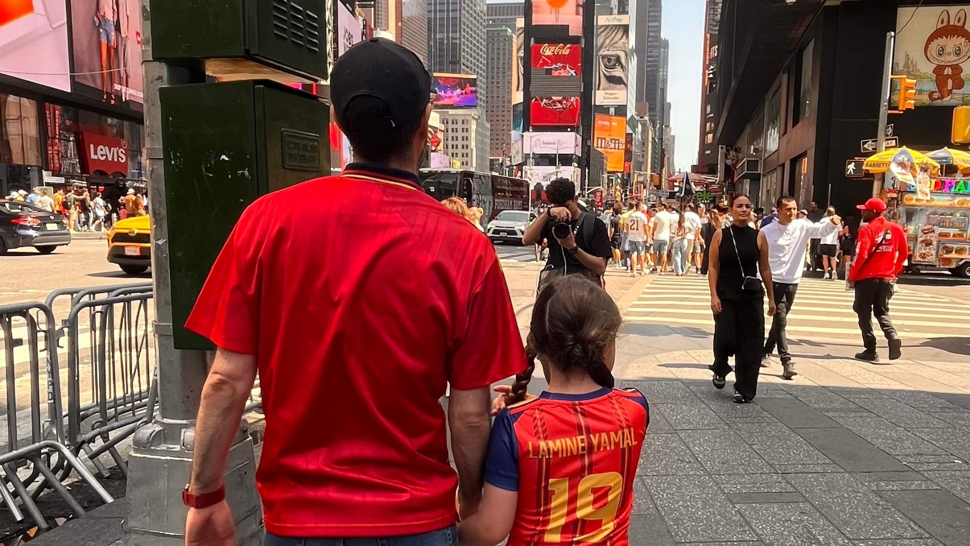 Adulto y niña caminando de la mano por Times Square