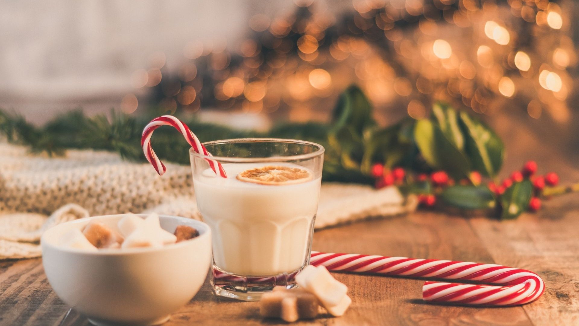 Vaso de bebida cremosa eggnog con una rodaja de naranja y un bastón de caramelo