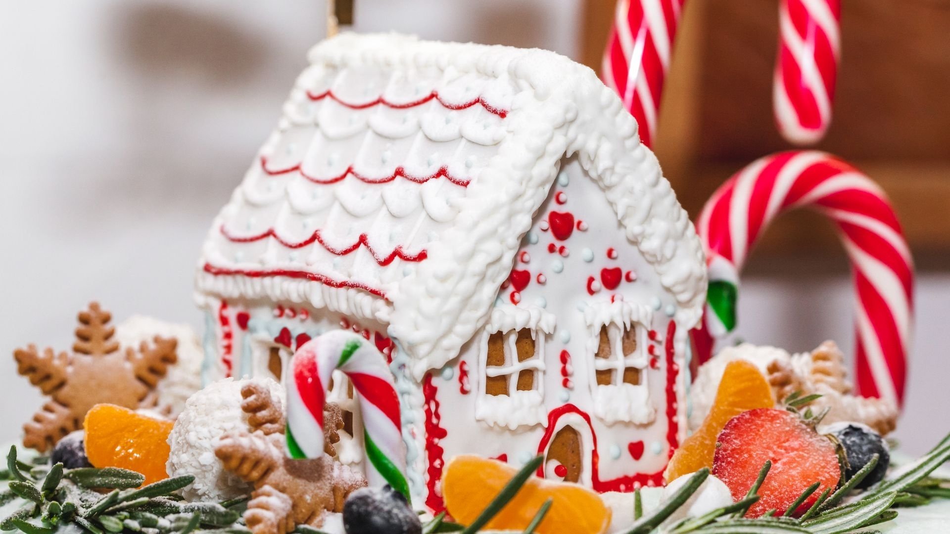 Casa de jengibre decorada con glaseado blanco y bastones de caramelo