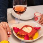 Dos personas se dan la mano sobre una mesa con un plato de pasta y copas.