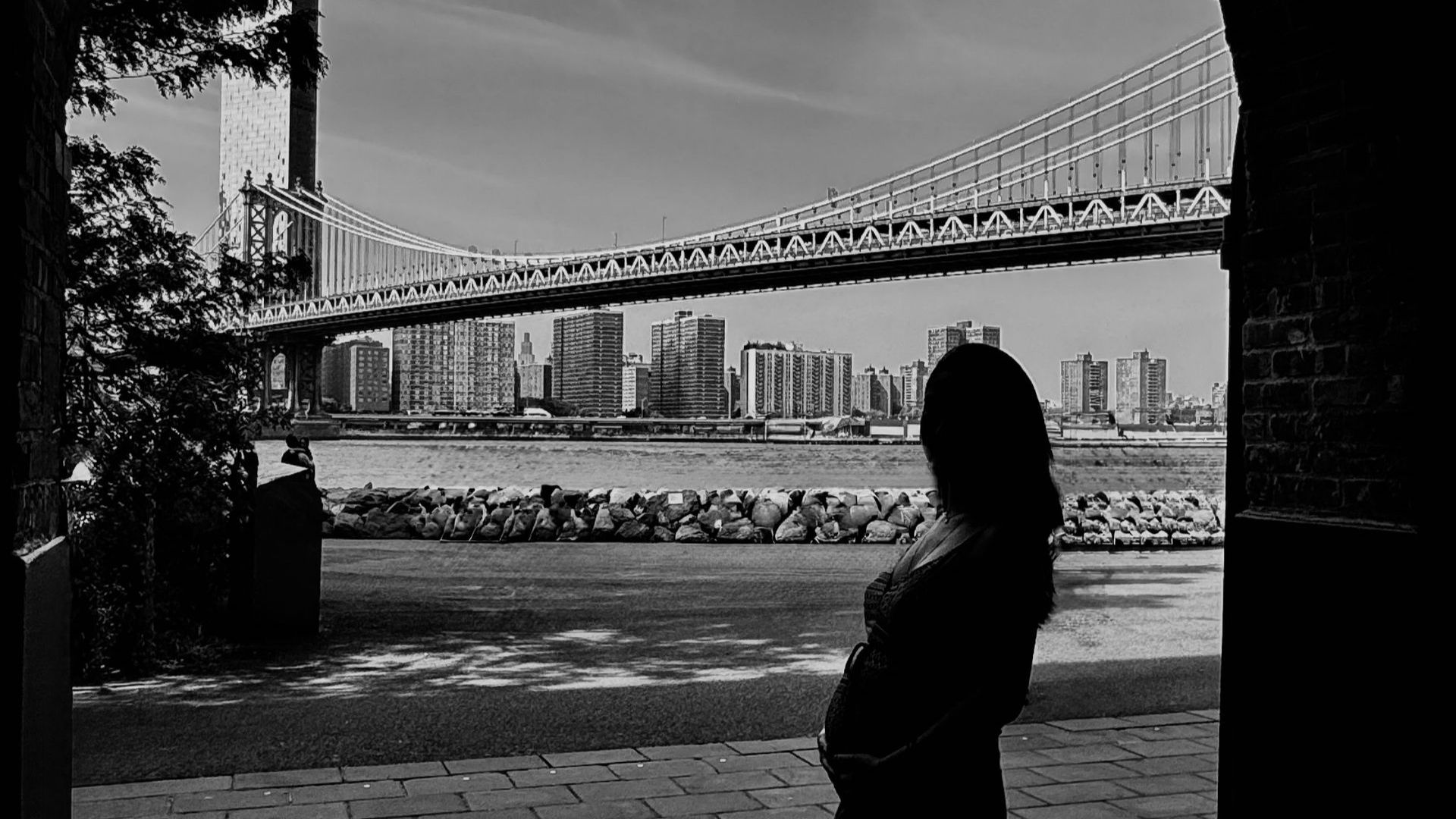 Silueta de una mujer embarazada en DUMBO con el Manhattan Bridge al fondo