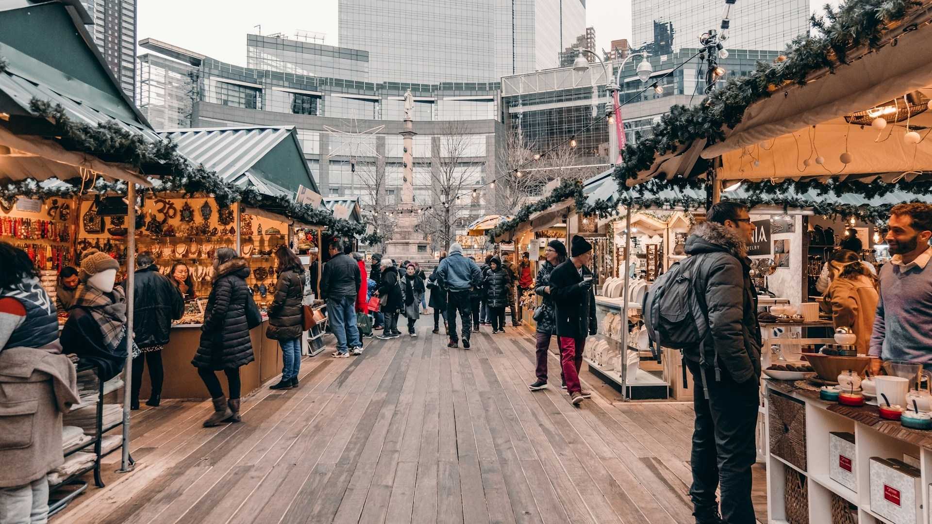 Puestos con guirnaldas y visitantes en el mercadillo de Columbus Circle